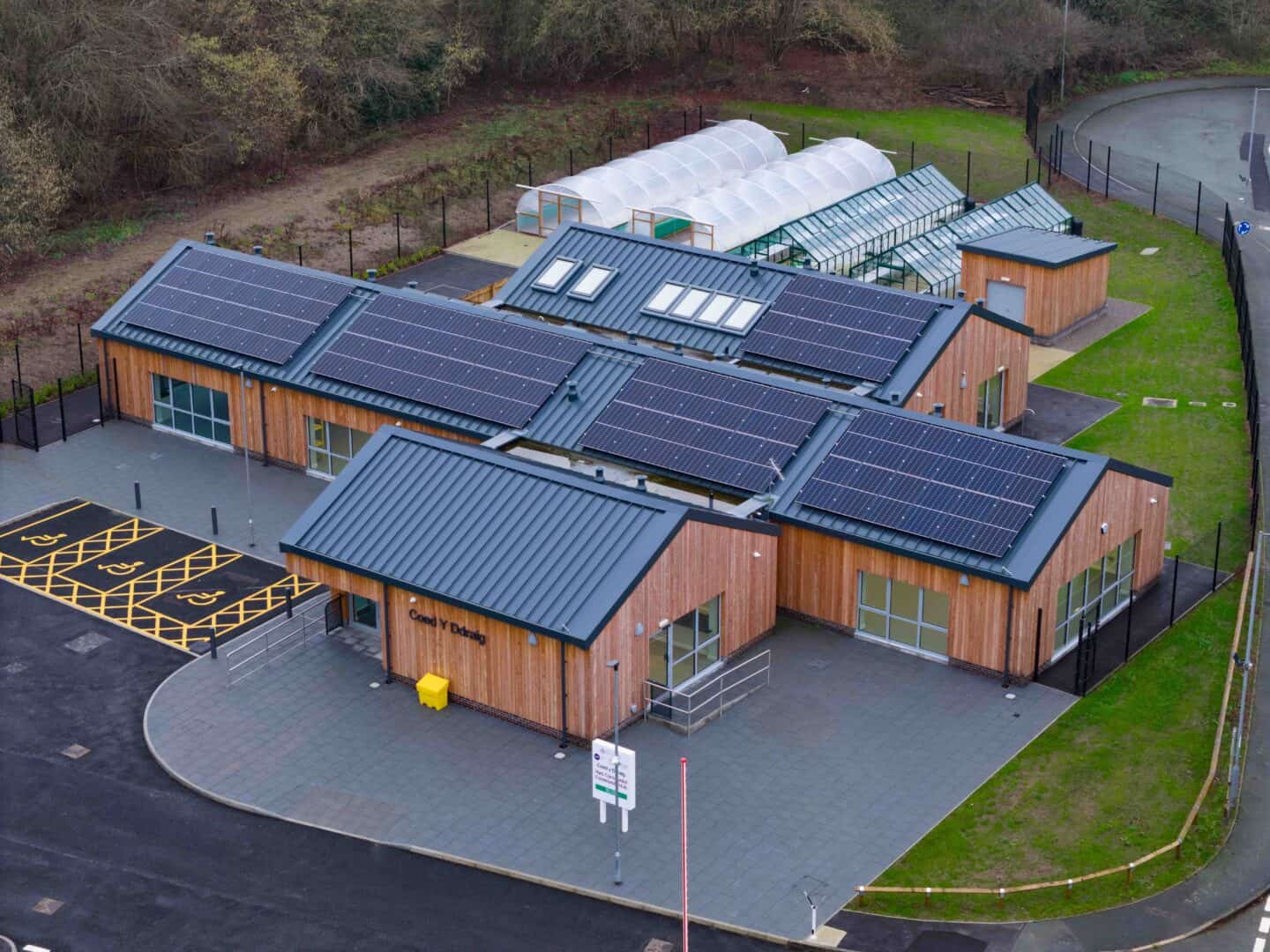 Modern building with extensive solar panel installation and greenhouses.