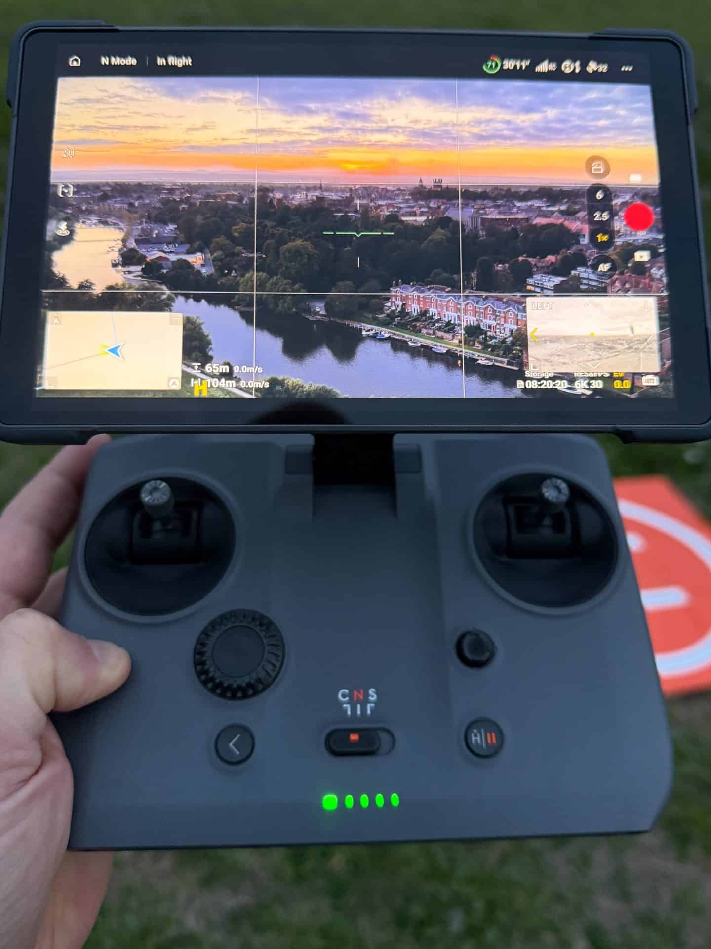 Drone capturing scenic landscape with river and sunset sky.