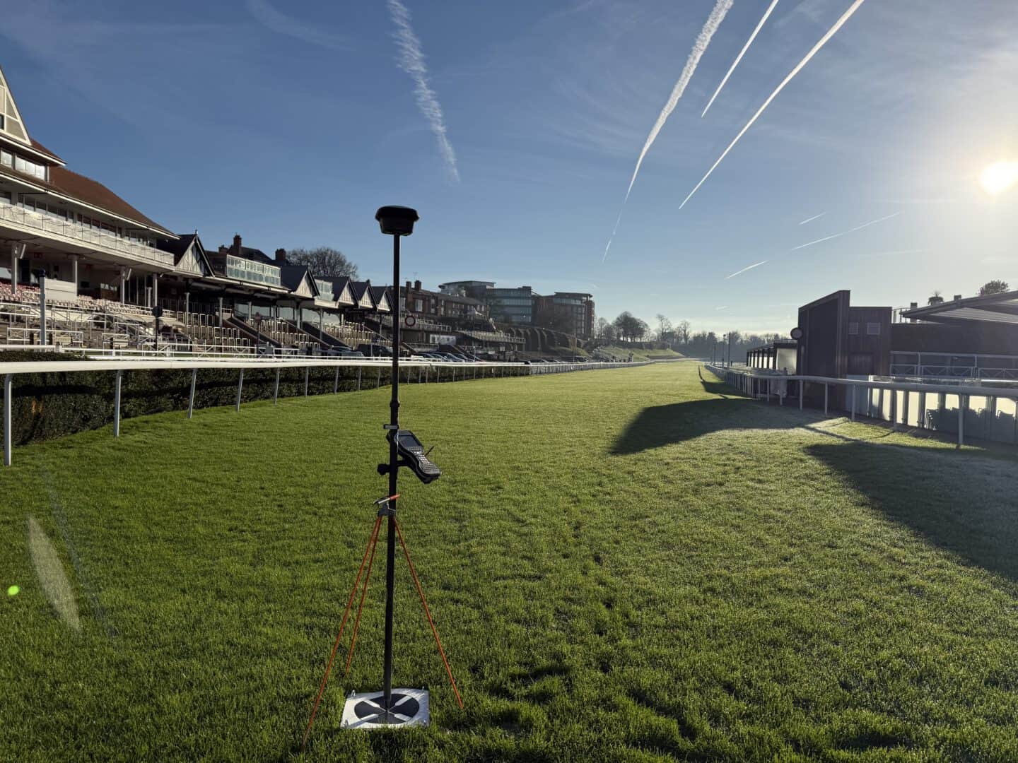 View of Chester Racecourse with green turf and grandstands under a clear sky.