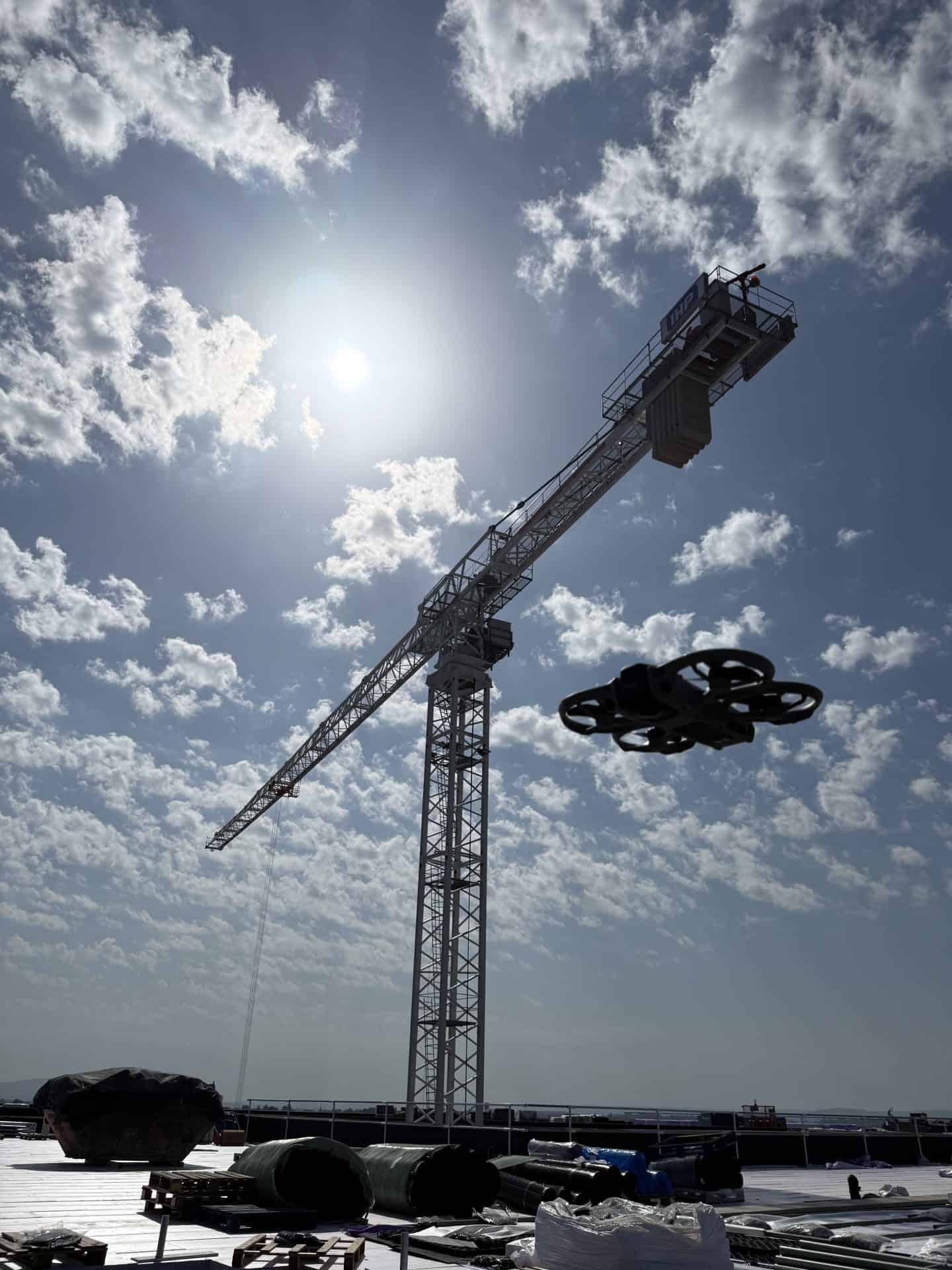 Construction crane on site with blue sky and clouds, highlighting building project.
