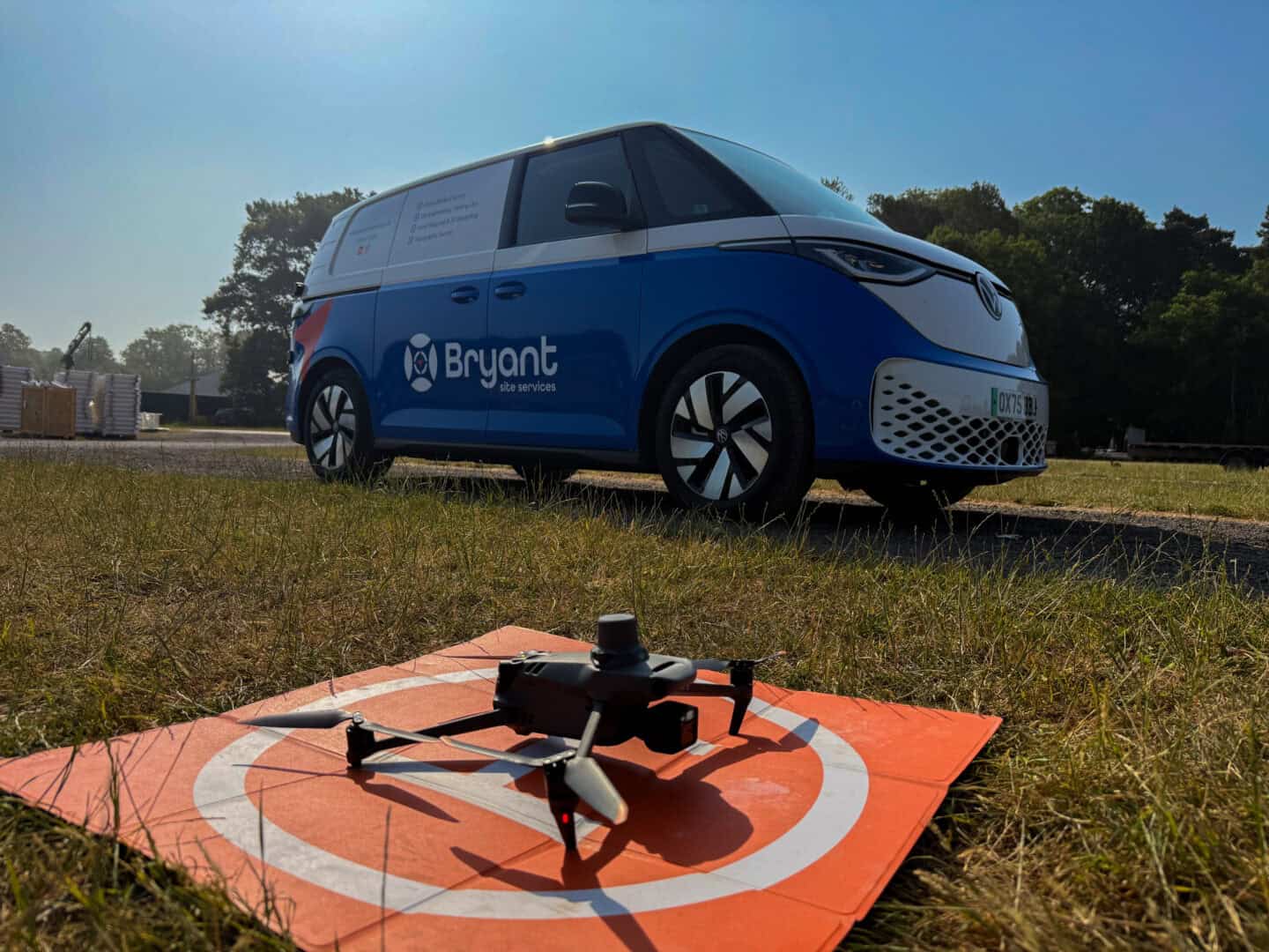 Electric delivery van with Bryant Site Services logo and a drone on the ground.