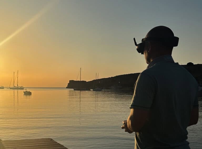 Man with drone flying over water at sunset for site inspection.