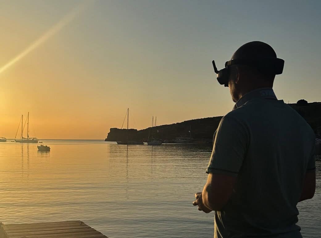 Man with drone flying over water at sunset for site inspection.