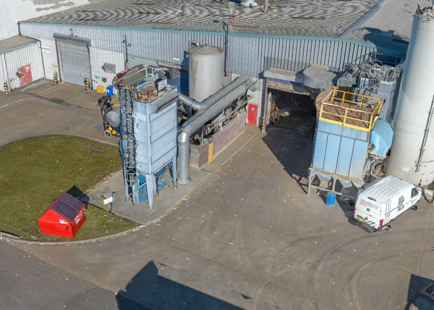 Industrial site with machinery, storage tanks, and a service van.