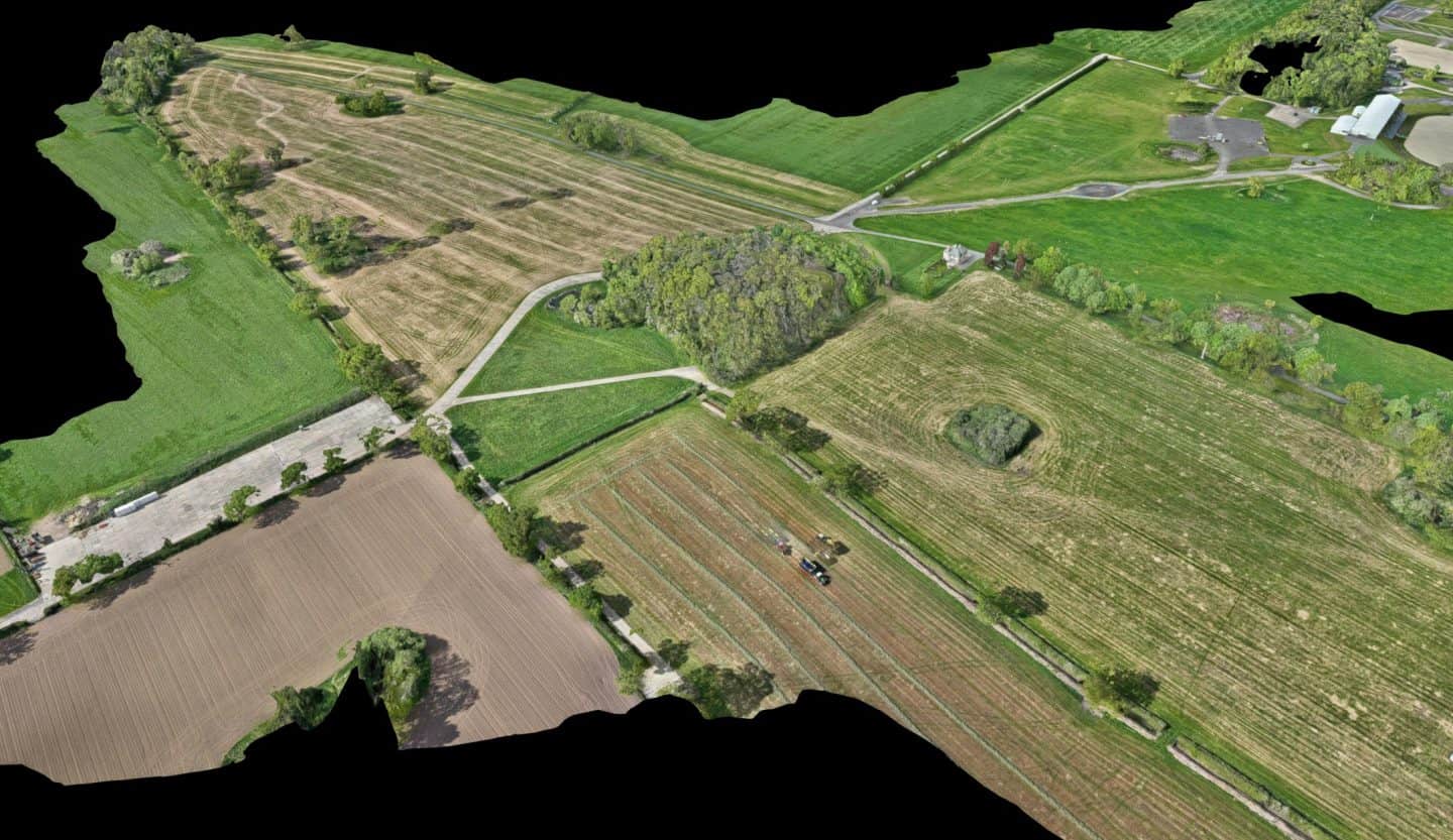 Aerial view of rural farmland and green fields with roads and trees.