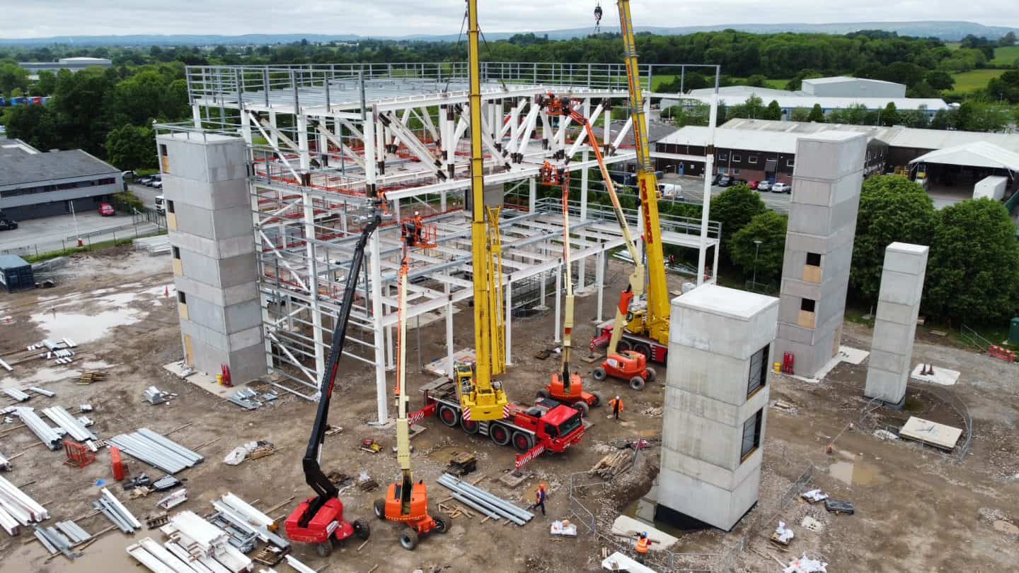 Construction site with cranes and steel framework in progress.