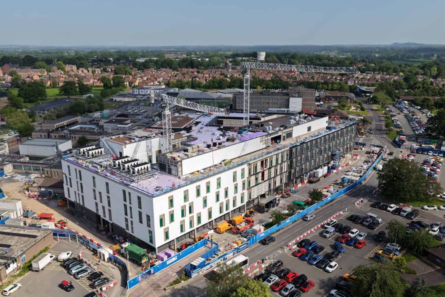 Aerial view of a modern construction site with a large building and parking lot.
