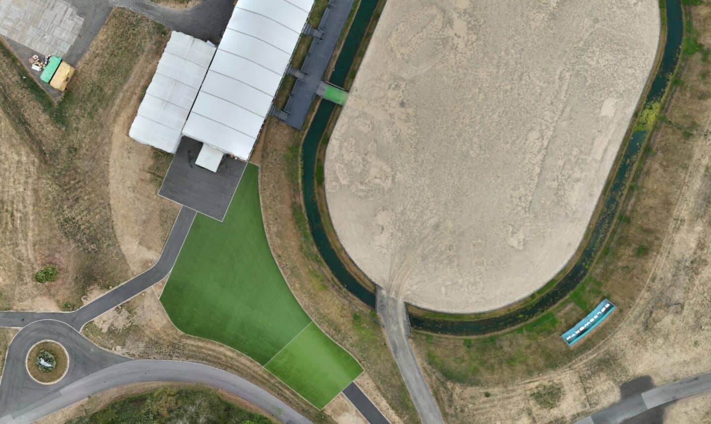 Aerial view of construction site with green areas and pathways.