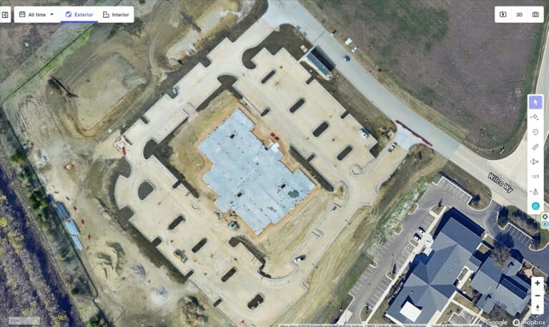 Construction site with building foundation and surrounding area.