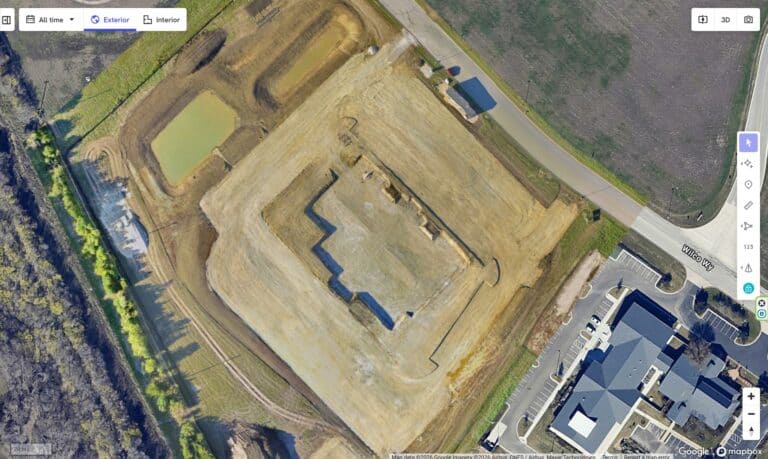 Aerial view of a construction site with building foundation and surrounding area.