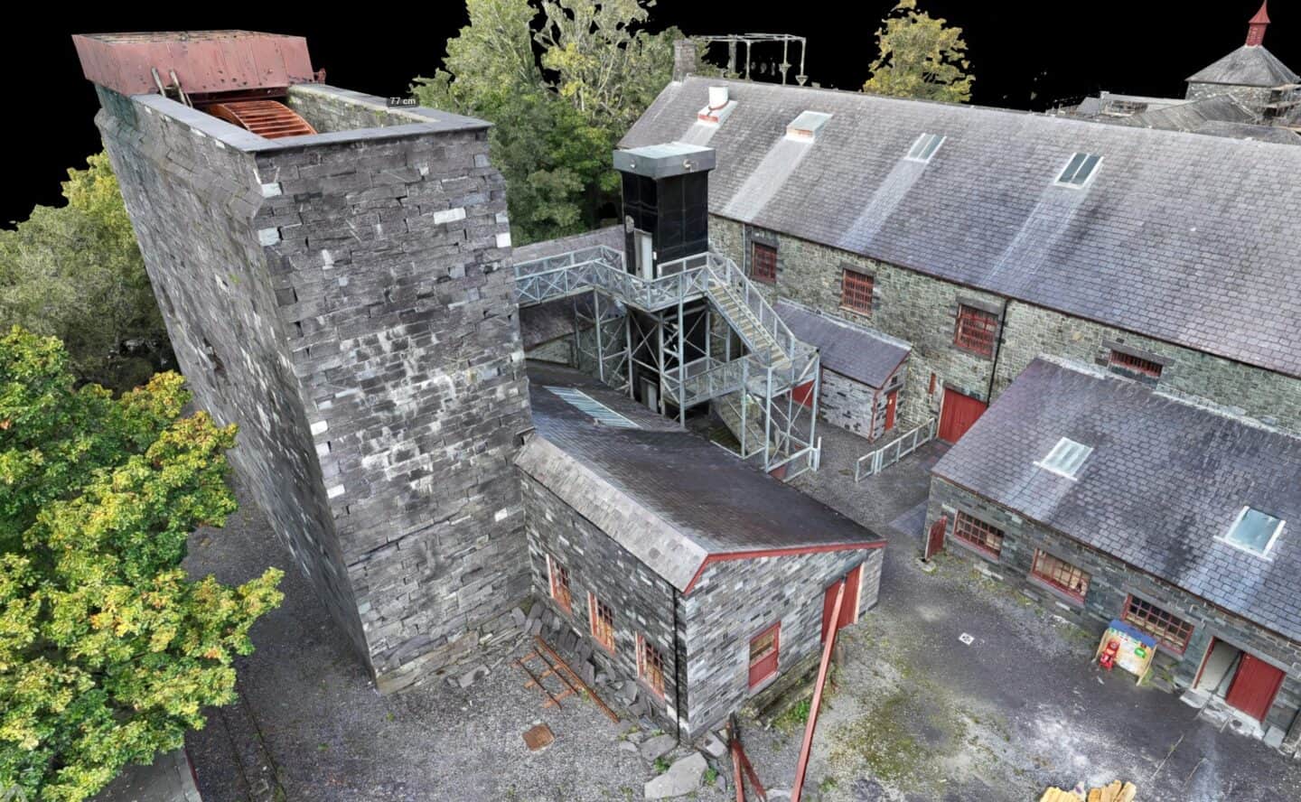 Aerial view of a historic stone mill with surrounding trees and buildings.